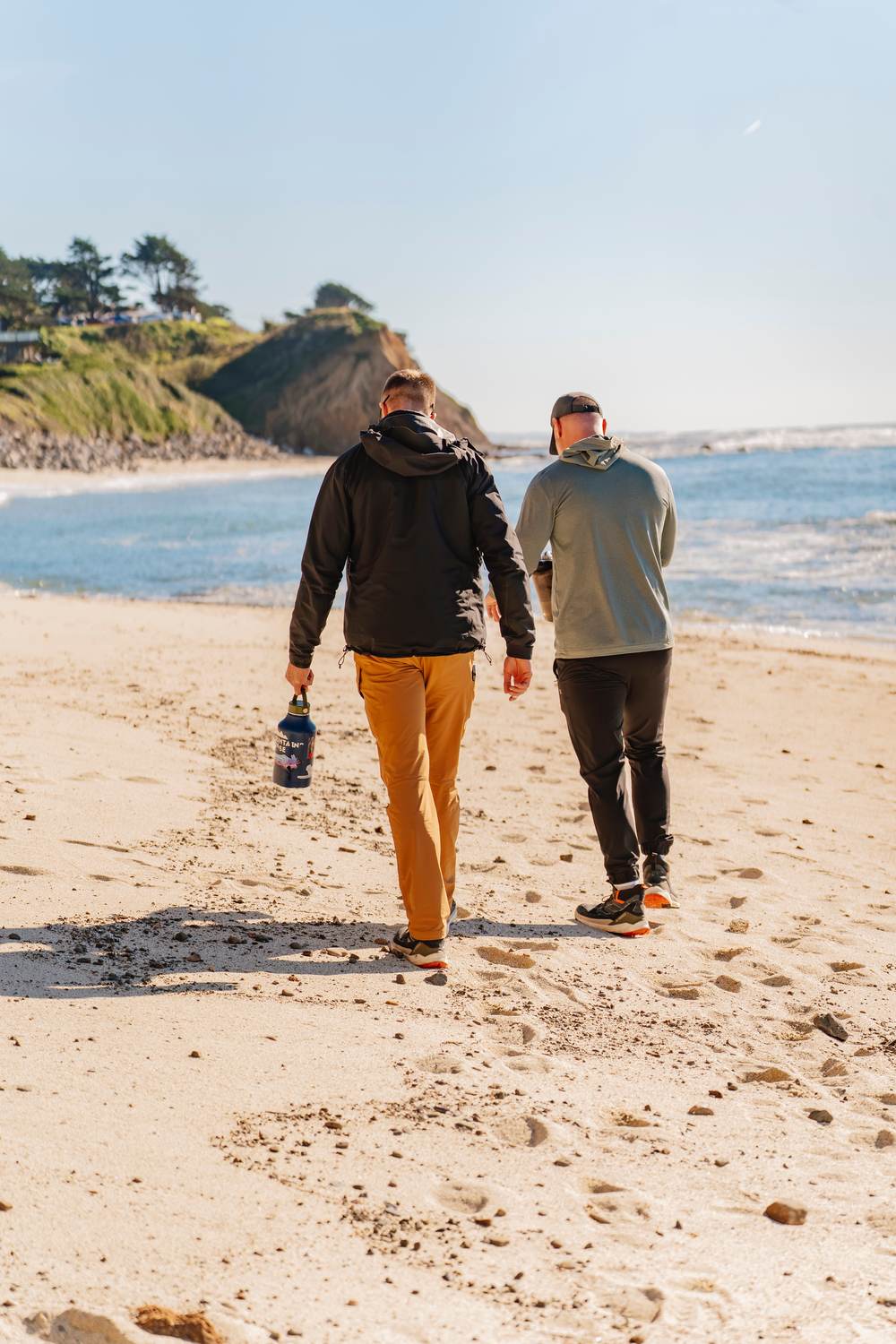 Two men walking away down the beach